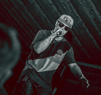 I’m on stage performing with a microphone, wearing a baseball cap and a streetwear outfit.